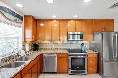a kitchen with wooden cabinets and stainless steel appliances at New! Iguana Palms - Private beach - Pet Freindly! in Panama City Beach