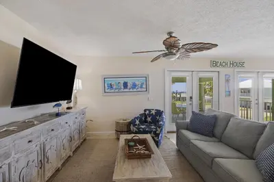 a living room with a couch and a flat screen tv at New! Iguana Palms - Private beach - Pet Freindly! in Panama City Beach