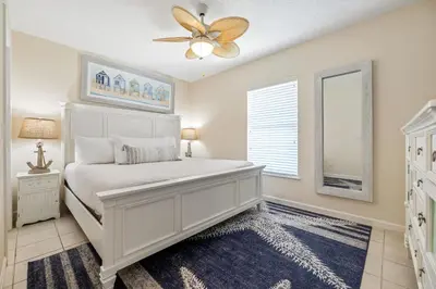 a bedroom with a white bed and a ceiling fan at New! Iguana Palms - Private beach - Pet Freindly! in Panama City Beach