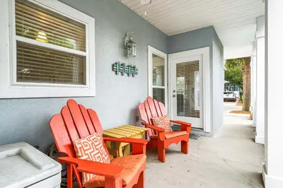 two chairs and a table on the porch of a house at Beach Bummin' - Week long stays get 4 free bikes rental! in Rosemary Beach