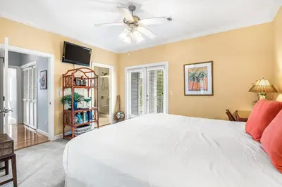 a bedroom with a white bed and a ceiling fan at Beach Bummin' - Week long stays get 4 free bikes rental! in Rosemary Beach