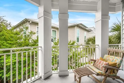 a porch with a rocking chair and a house at Beach Bummin' - Week long stays get 4 free bikes rental! in Rosemary Beach