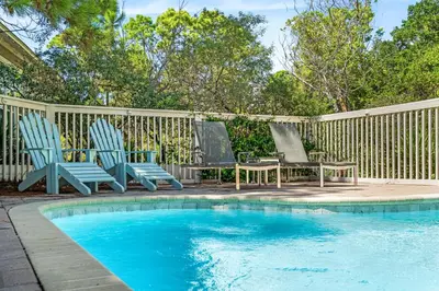 a pool with two chairs and a table next to a fence at Amaryllis Point - 30A, Private Pool, Bicycles, 3 King Masters! in Rosemary Beach