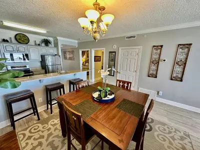 a dining room and kitchen with a wooden table and chairs at Ocean Reef 1607 in Panama City Beach