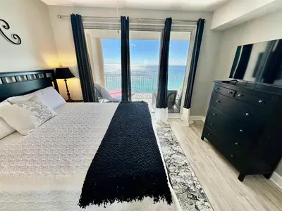 a bedroom with a bed and a dresser with a large window at Ocean Reef 1607 in Panama City Beach