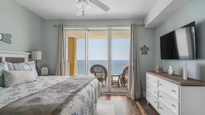 a bedroom with a bed and a view of the ocean at Tropic Winds 2101 in Panama City Beach