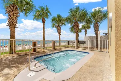 a swimming pool with palm trees and a fence at Tropic Winds 2101 in Panama City Beach