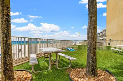 a picnic table and two trees with a playground at Tropic Winds 2101 in Panama City Beach