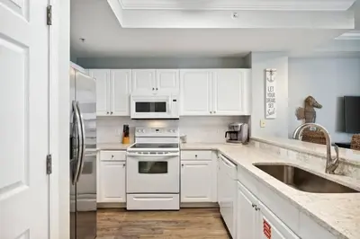 a kitchen with white cabinets and a stove and a sink at Tidewater 1406 in Panama City Beach
