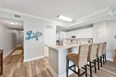 a kitchen with a bar with chairs and a counter at Tidewater 1406 in Panama City Beach