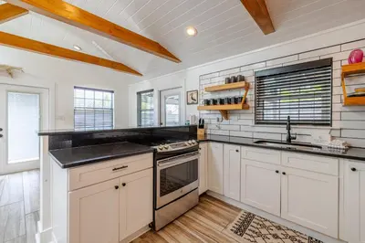 a kitchen with white cabinets and black counter tops at Bayview Cottage - Sun deck, pool, and more! in Panama City Beach