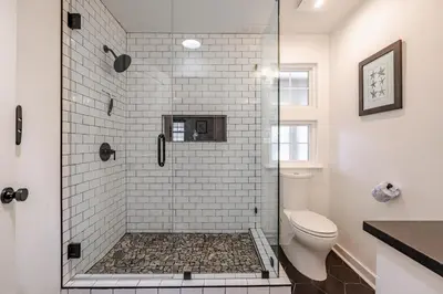 a white bathroom with a shower with a toilet at Bayview Cottage - Sun deck, pool, and more! in Panama City Beach