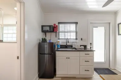 a kitchen with a stainless steel refrigerator and white cabinets at Bayview Cottage - Sun deck, pool, and more! in Panama City Beach