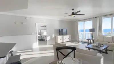 a living room with white furniture and a ceiling fan at Calypso 1-1709 by Emerald Coast Retreats in Panama City Beach