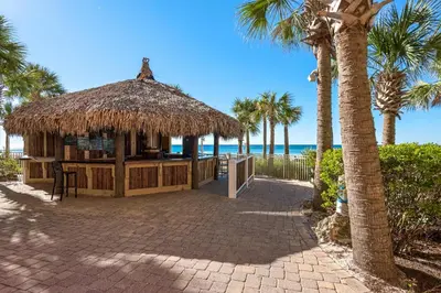a hut on the beach with palm trees and the ocean at Calypso 1-1709 by Emerald Coast Retreats in Panama City Beach