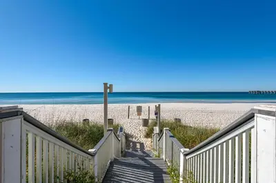 a stairway leading to a sandy beach with the ocean at Calypso 1-1709 by Emerald Coast Retreats in Panama City Beach