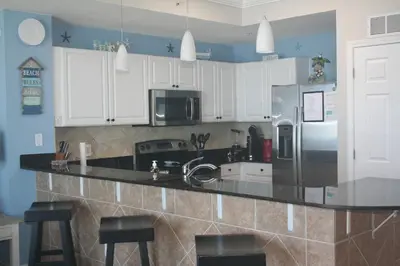 a kitchen with white cabinets and black counter tops at Panama City Beach, Beach Front Condo 207 in Panama City Beach