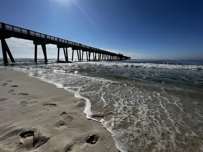 a pier on the beach with footprints in the sand at Panama City Beach, Beach Front Condo 207 in Panama City Beach