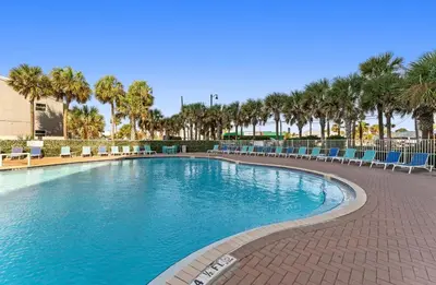 a large swimming pool with chairs and palm trees at Panama City Beach, Beach Front Condo 207 in Panama City Beach