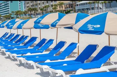 a row of blue and white chairs and umbrellas on a beach at Panama City Beach, Beach Front Condo 207 in Panama City Beach