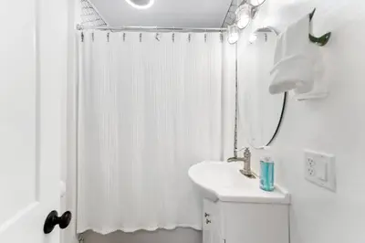 a white bathroom with a shower curtain and a sink at a block away from beach/Harbor/Fine restaurants in Panama City