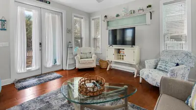 a living room with a tv and a couch and a table at Walking on Waves in Santa Rosa Beach