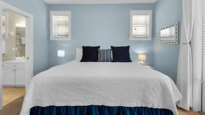 a bedroom with a white bed with blue walls at Walking on Waves in Santa Rosa Beach