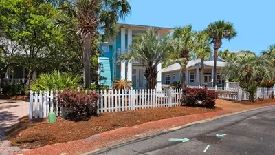 a white picket fence in front of a house at Walking on Waves in Santa Rosa Beach