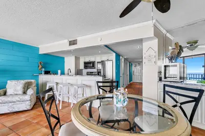 a kitchen and living room with a glass table at Edgewater Tower 1-608 in Panama City Beach