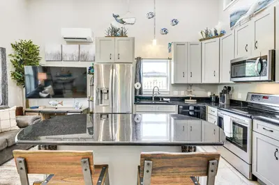 a large kitchen with white cabinets and a counter top at 13 Mi to St Andrews State Park Cabin with Patio! in Panama City