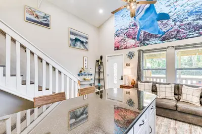 a living room with a staircase and a couch at 13 Mi to St Andrews State Park Cabin with Patio! in Panama City