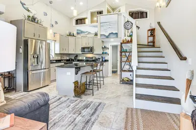 a kitchen and living room with a spiral staircase at 13 Mi to St Andrews State Park Cabin with Patio! in Panama City