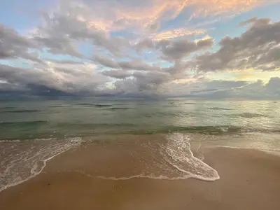a beach with a cloudy sky and the ocean at Vitamin Sea -Heart of Rosemary Beach. in Rosemary Beach