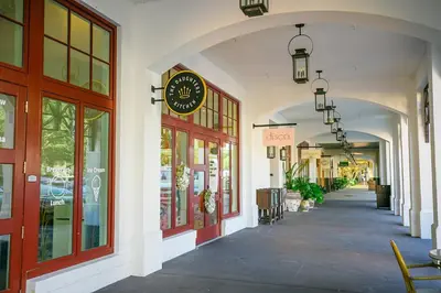 an arcade with a clock on the side of a building at Vitamin Sea -Heart of Rosemary Beach. in Rosemary Beach