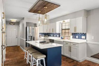 a kitchen with white cabinets and a blue island with stools at Caribbean feel,Mini&Disc Golf,Heated Pool,Game Rom in Panama City Beach