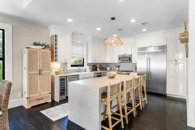 a kitchen with white cabinets and a kitchen island with chairs at 99 Sandy Shores Ct in Inlet Beach