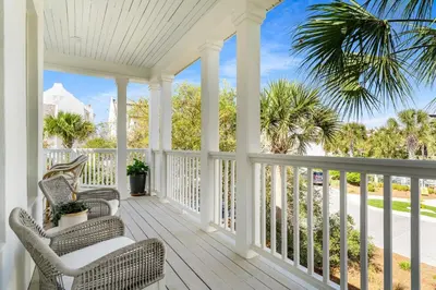 a porch with two chairs and palm trees at 99 Sandy Shores Ct in Inlet Beach