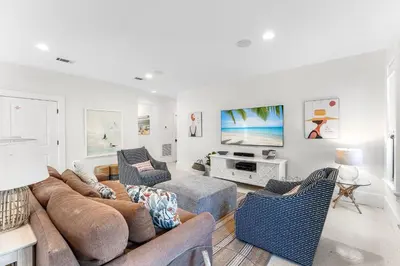 a living room with a couch and chairs and a tv at 99 Sandy Shores Ct in Inlet Beach