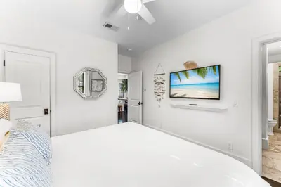 a white bedroom with a bed and a flat screen tv at 99 Sandy Shores Ct in Inlet Beach