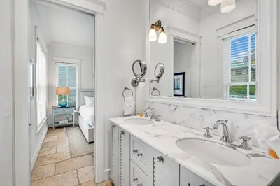 a white bathroom with a sink and a mirror at Treetop Cottage in Rosemary Beach