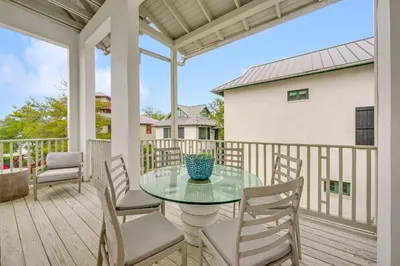a patio with a glass table and chairs on a deck at Treetop Cottage in Rosemary Beach
