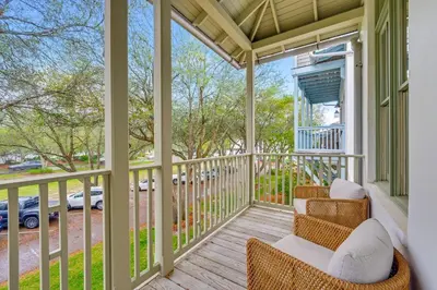 a screened porch with two chairs and a view of a street at Treetop Cottage in Rosemary Beach