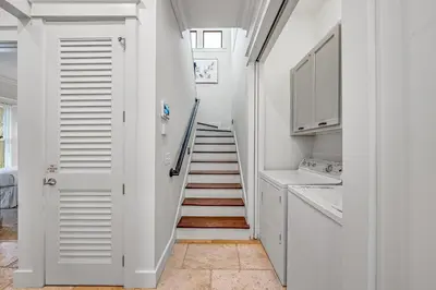 a staircase in a kitchen with white cabinets at Treetop Cottage in Rosemary Beach