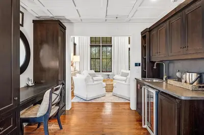 a kitchen with wooden cabinets and a living room at Treetop Cottage in Rosemary Beach