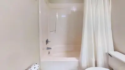 a bathroom with a white shower curtain and a toilet at Commodore 0502 in Panama City Beach
