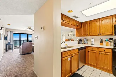 a kitchen with wooden cabinets and a dining room at Commodore 0502 in Panama City Beach