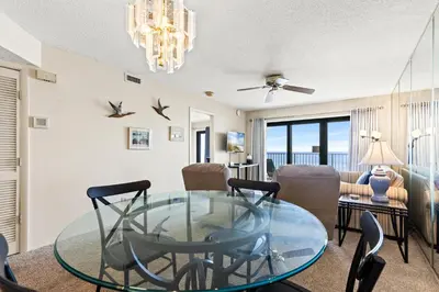 a living room with a glass table and chairs at Commodore 0502 in Panama City Beach