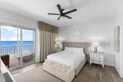a bedroom with a bed and a balcony with the ocean at Treasure Island #0401 in Panama City Beach