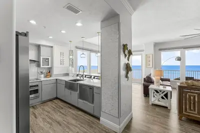 a kitchen and living room with a view of the ocean at Treasure Island #0401 in Panama City Beach