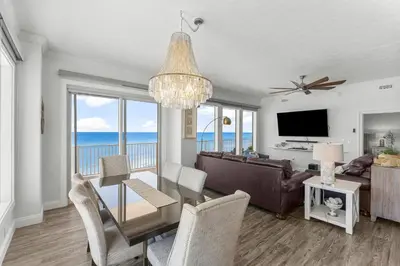 a living room with a dining room table with a view of the ocean at Treasure Island #0401 in Panama City Beach